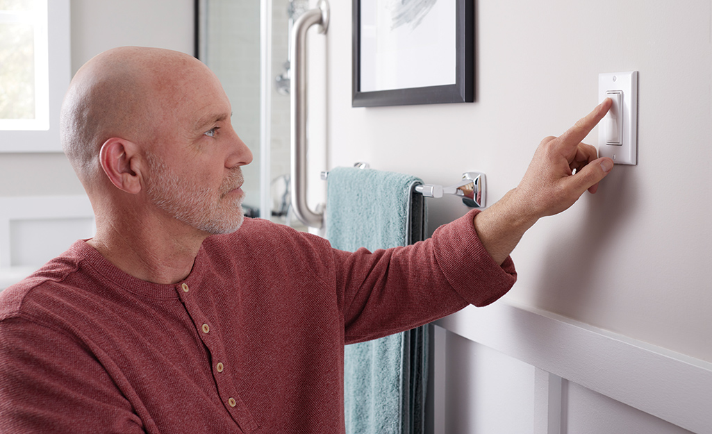 A man uses a button switch in an accessible bathroom.
