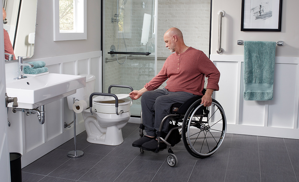 A man lifts a toilet lid in an accessible bathroom.