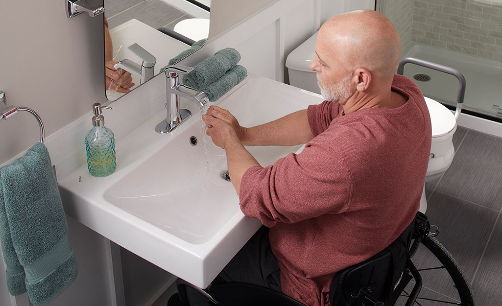 A man uses an accessible bathroom sink.
