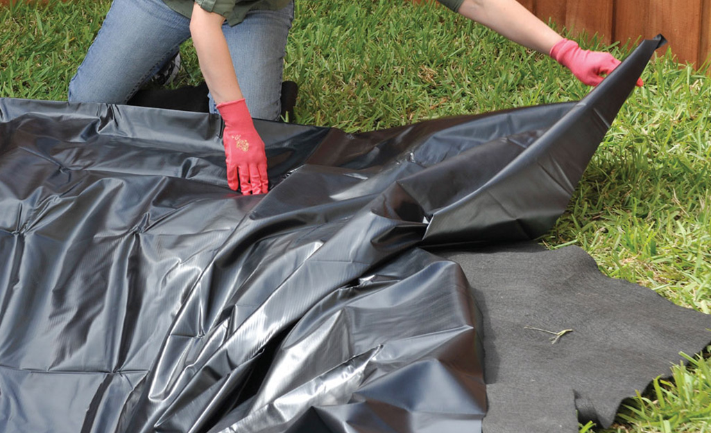 Someone unfolding a plastic liner to use in a bog garden. Someone unfolding a plastic liner to use in a bog garden.