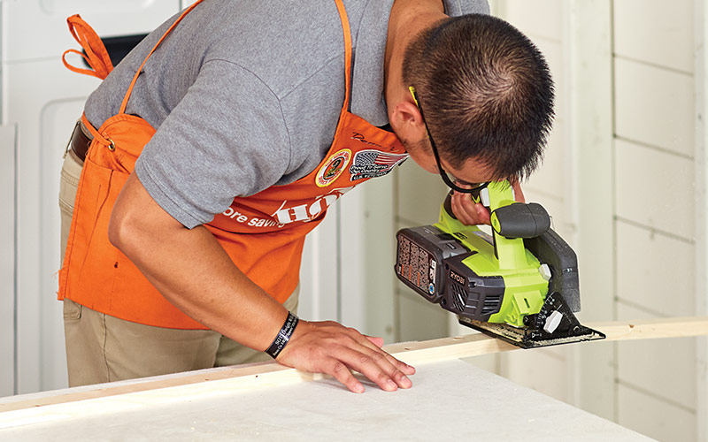 A man cutting a circular saw to cut a piece of wood. A man cutting a circular saw to cut a piece of wood.