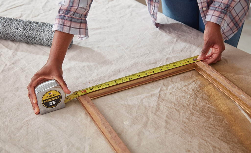 Person measures the frame with a tape measure