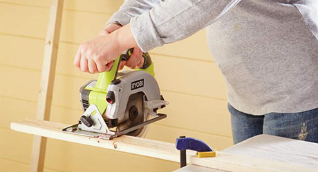 A person using a saw to cut a board.