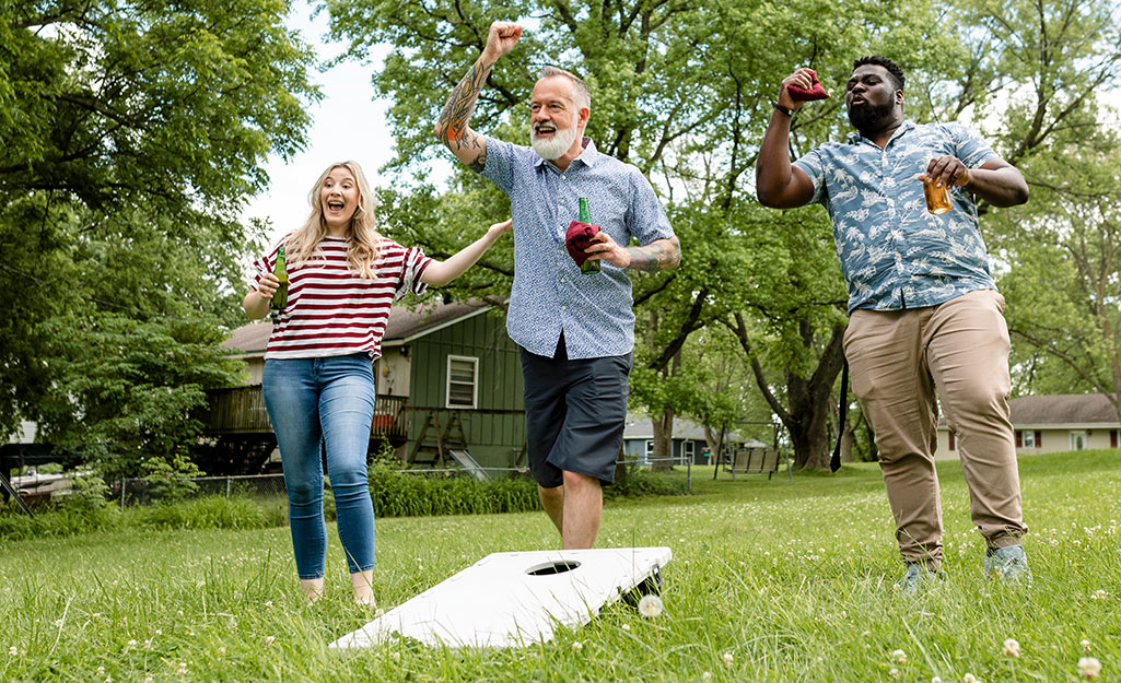 Three people playing a side in a corn hole game.