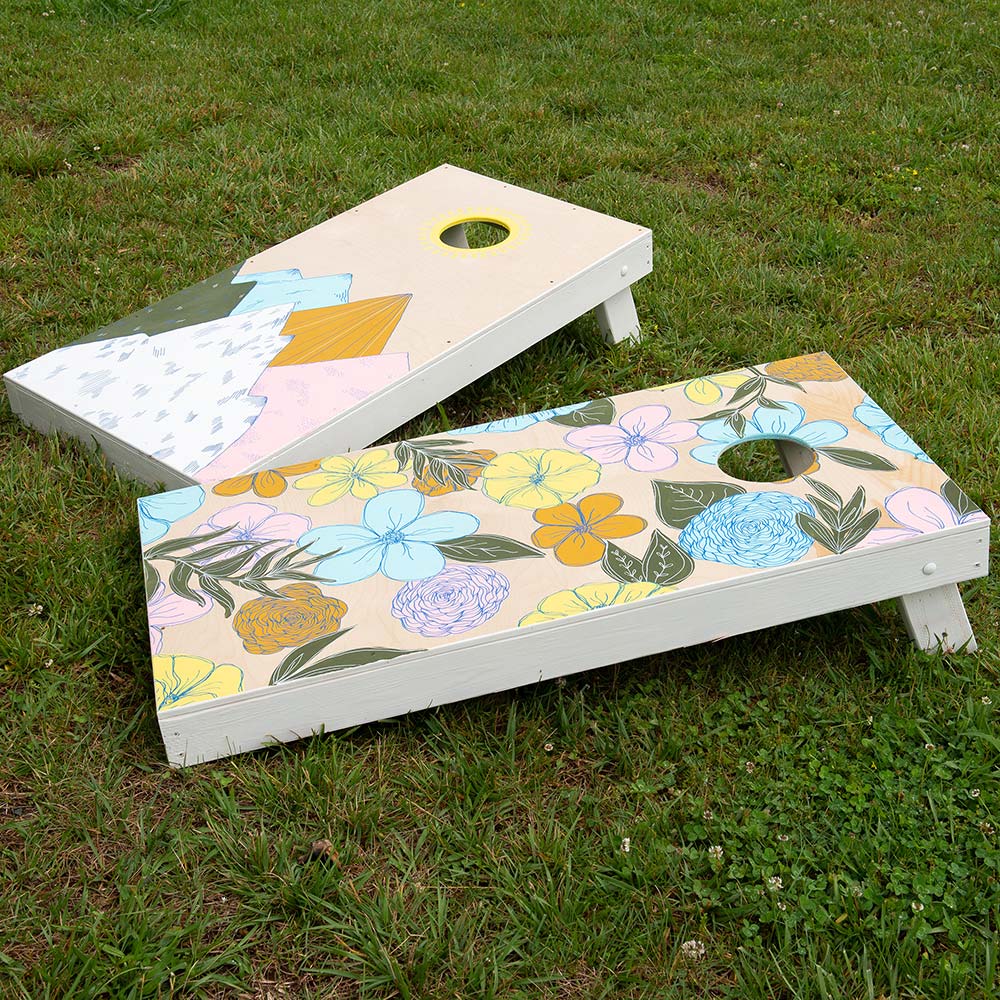 A cornhole target board sits on a lawn.