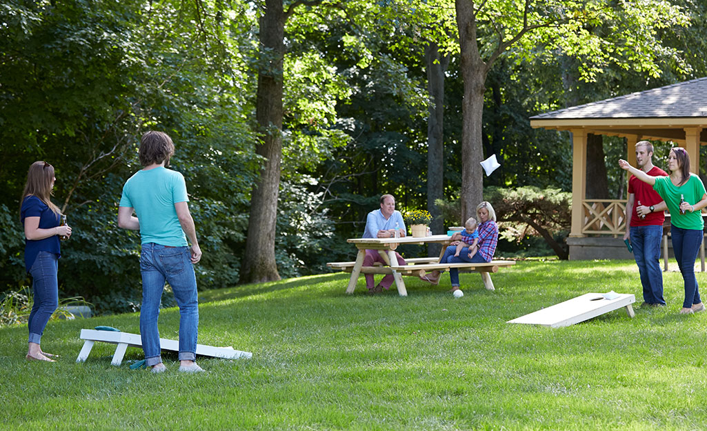 Friends playing the corn hole game in the backyard.