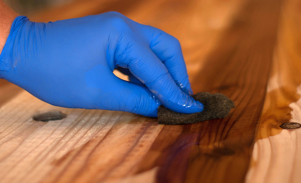 A hand rubs oil into the grain of a cutting board.