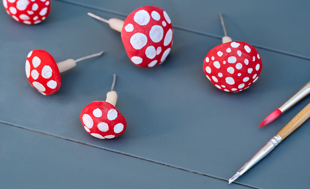 Five hand painted, miniature mushrooms lay on a table. 