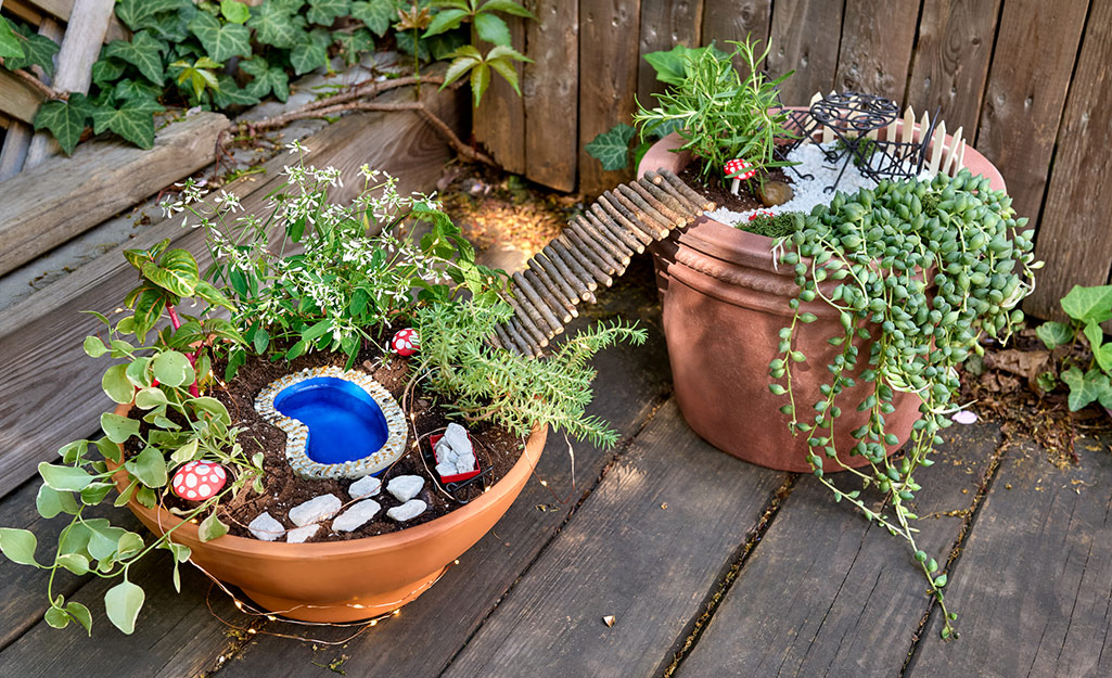 Two fairy gardens connected by a bridge made from twigs.