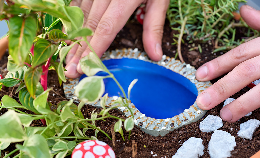 A small pond is added to a fairy garden. 