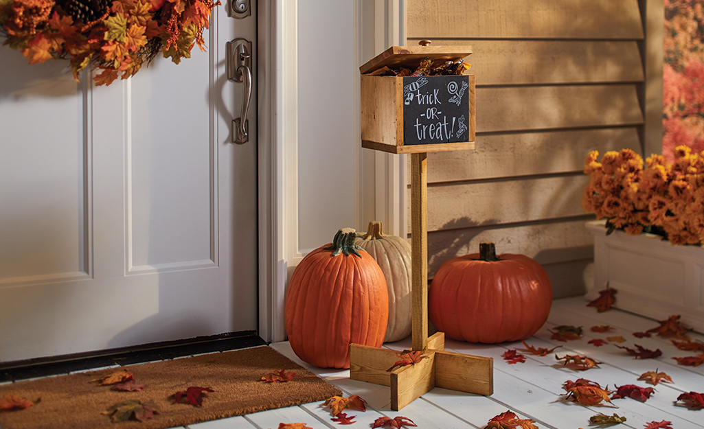 A finished halloween candy holder sits on a porch with pumpkins. 