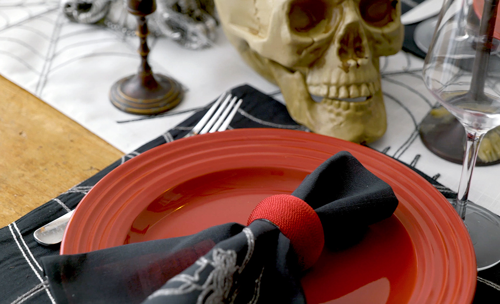 A black napkin with a red napkin ring sits atop a red plate. A black napkin with a red napkin ring sits atop a red plate.