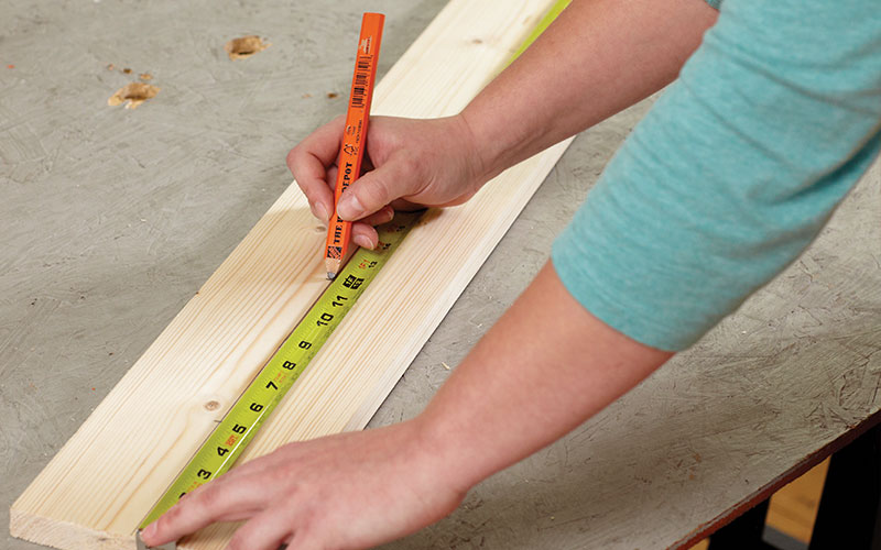 A person drawing a line down the center of a board.