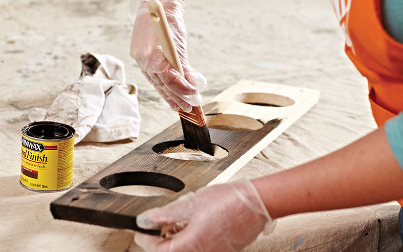 A person staining a board.