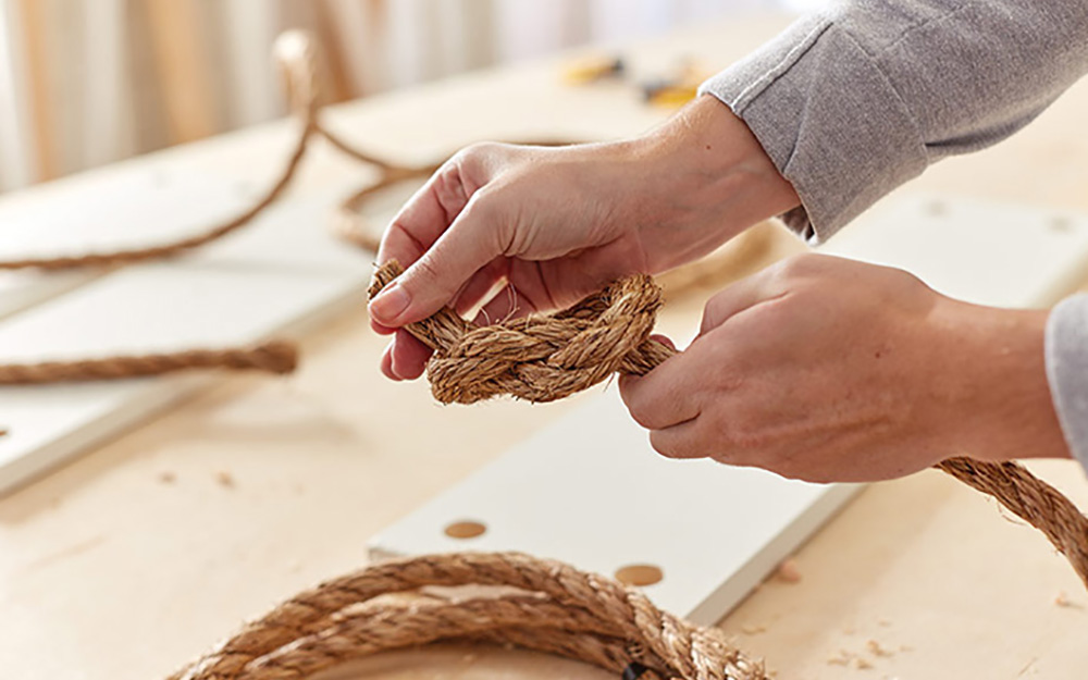 A person tying a knot in a length of rope.