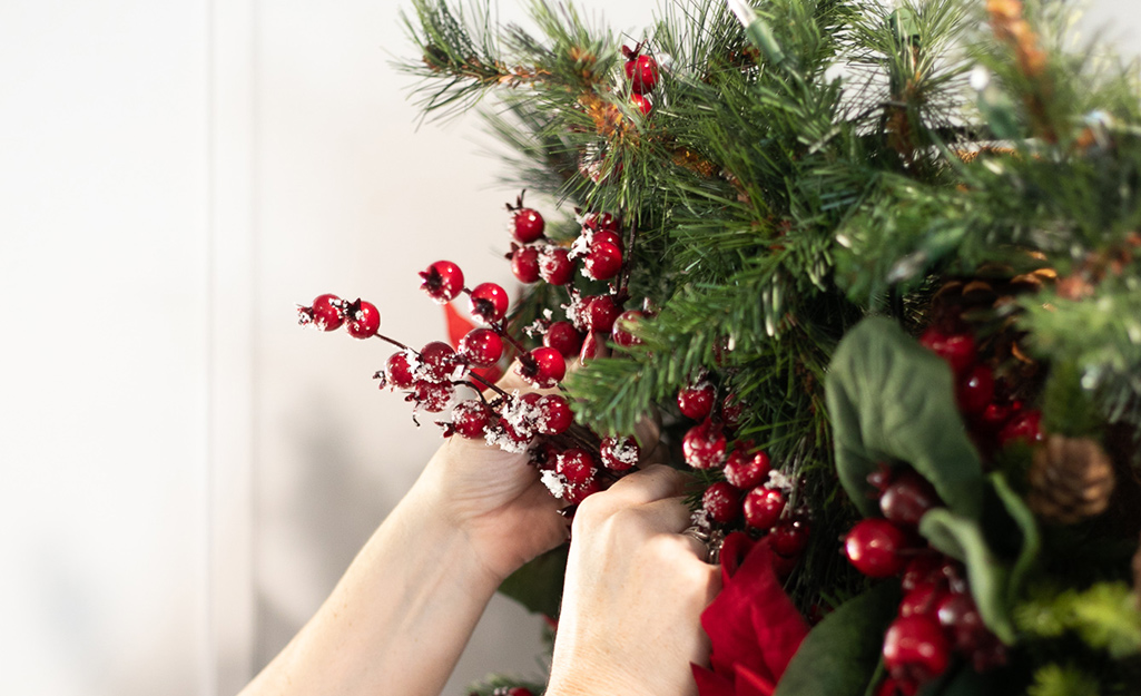 Holiday berry stems are added to garland.