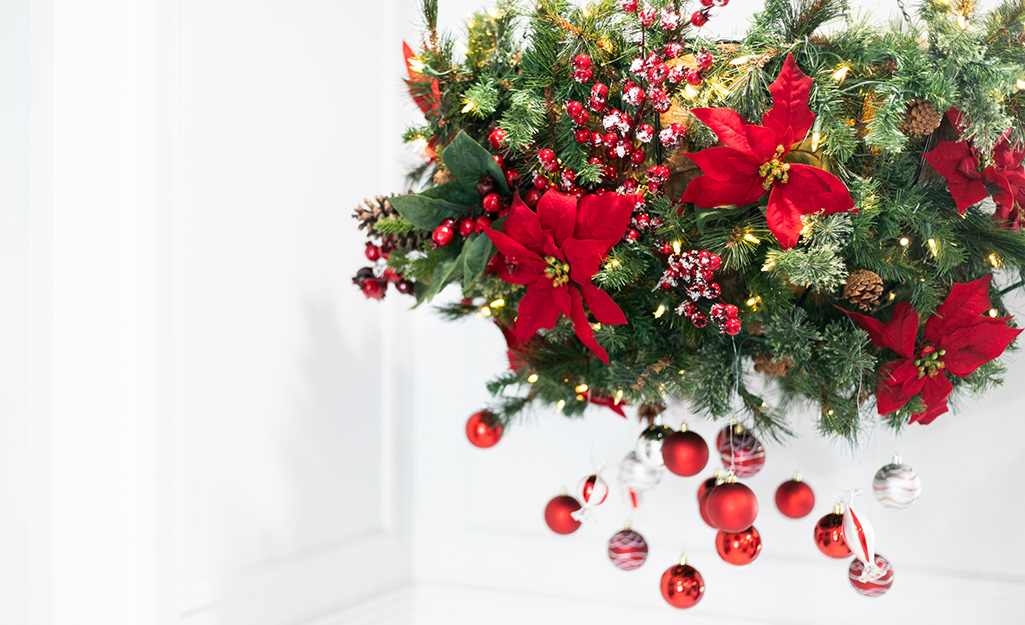 A finished hanging planter with garland, poinsettias, ornaments and berry stems.