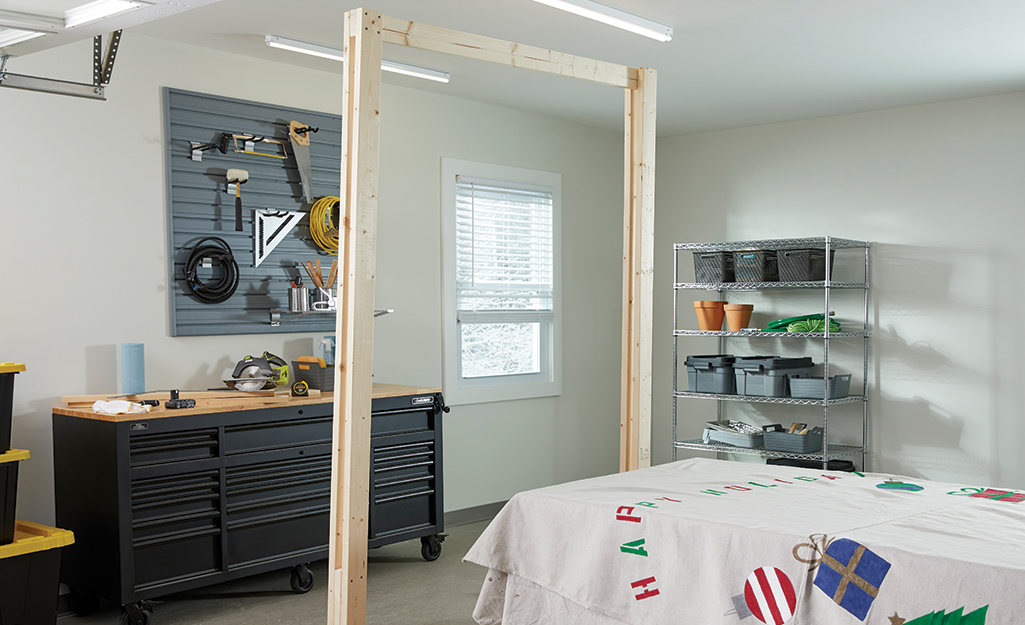 The wooden frame of a photo booth stands upright in a workshop.