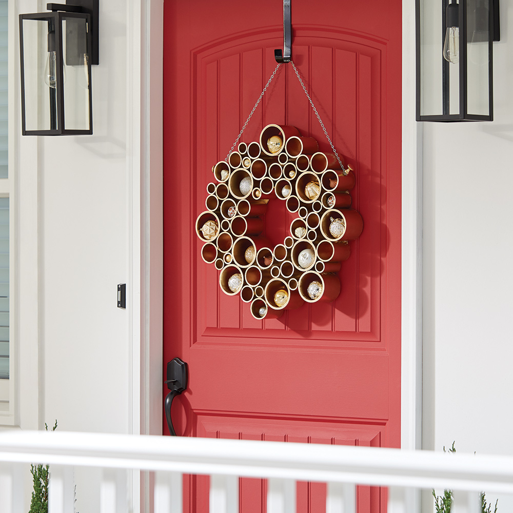 A gold PVC pipe holiday wreath hanging on a front door.