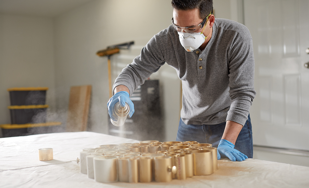 Man spray painting a PVC pipe holiday wreath gold.