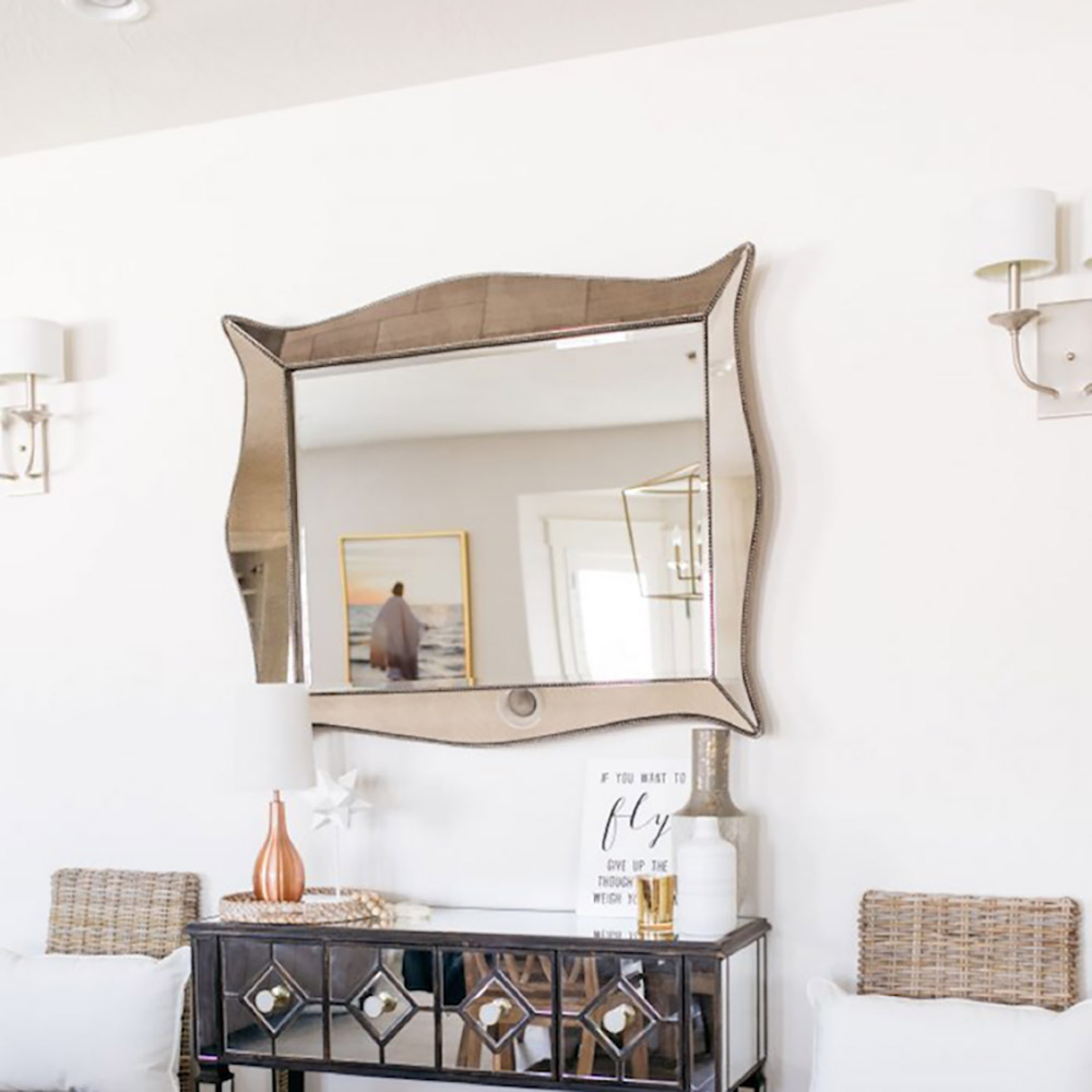 A large mirror hanging over a black and mirrored console table.
