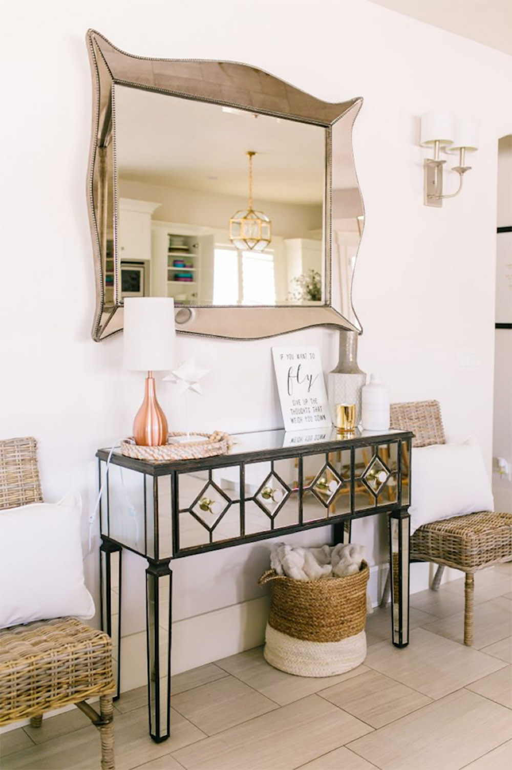 A dining room decorated with a mirrored console, accent chairs, and wall sconces.