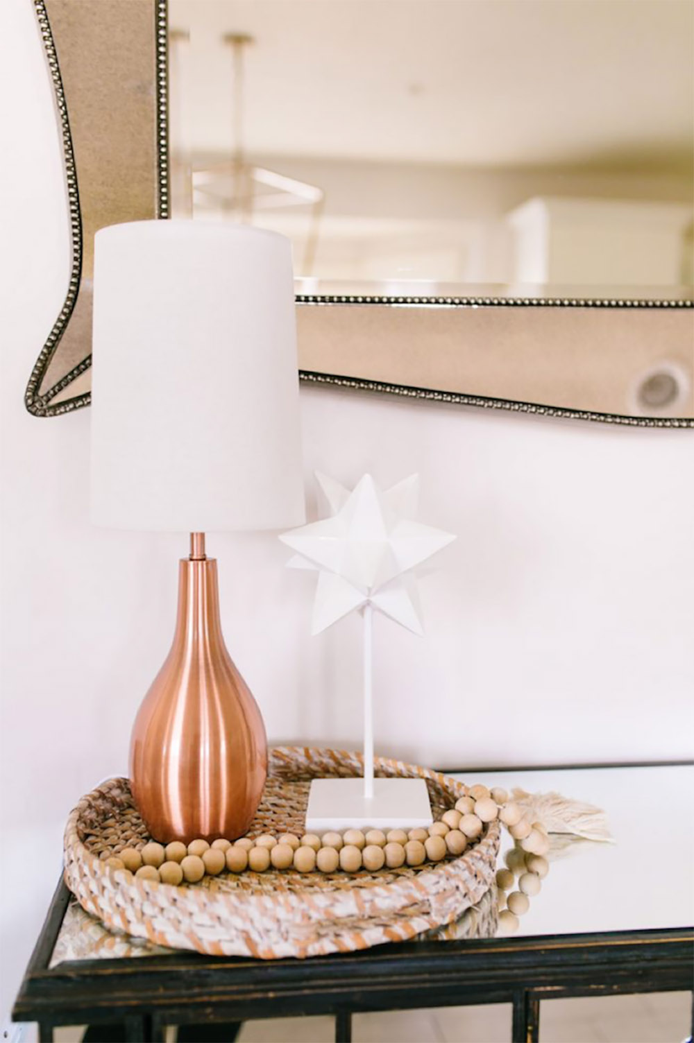 A rose gold lamp sitting on a decorative tray.