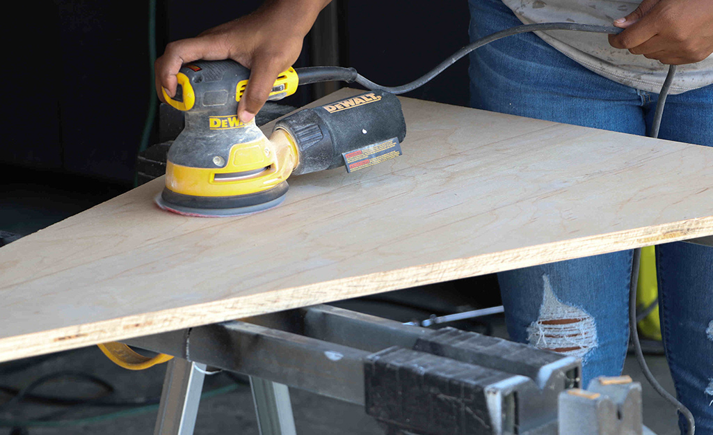 Wood is sanded with an orbital sander. 