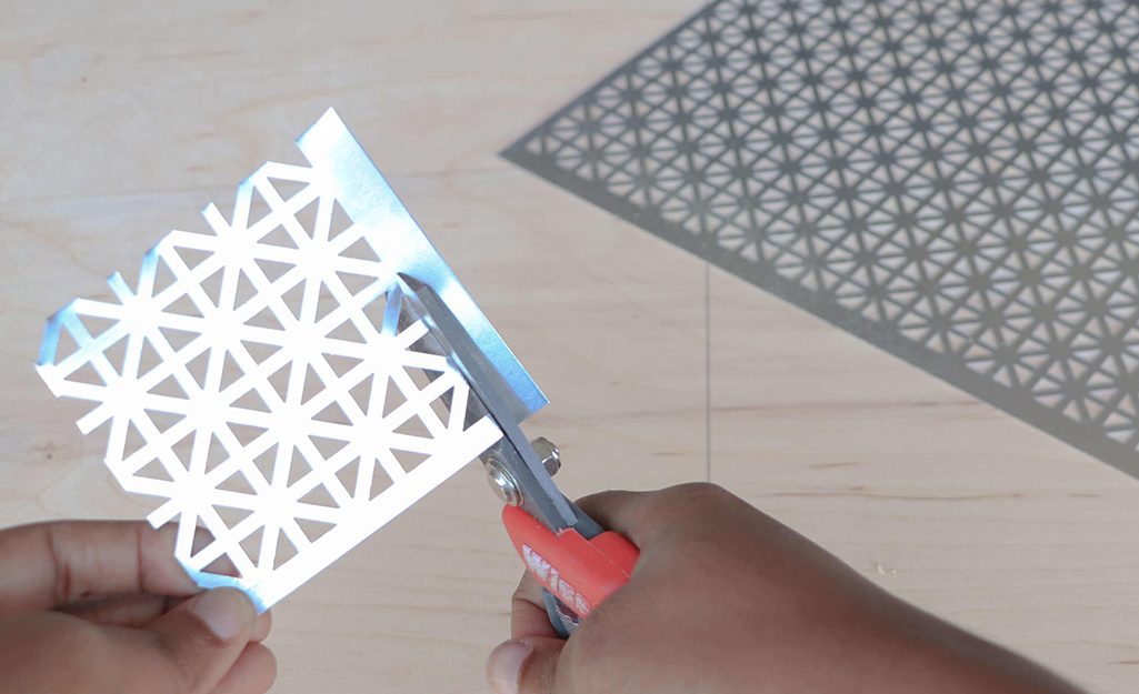 Metal snowflakes are cut out using snips.