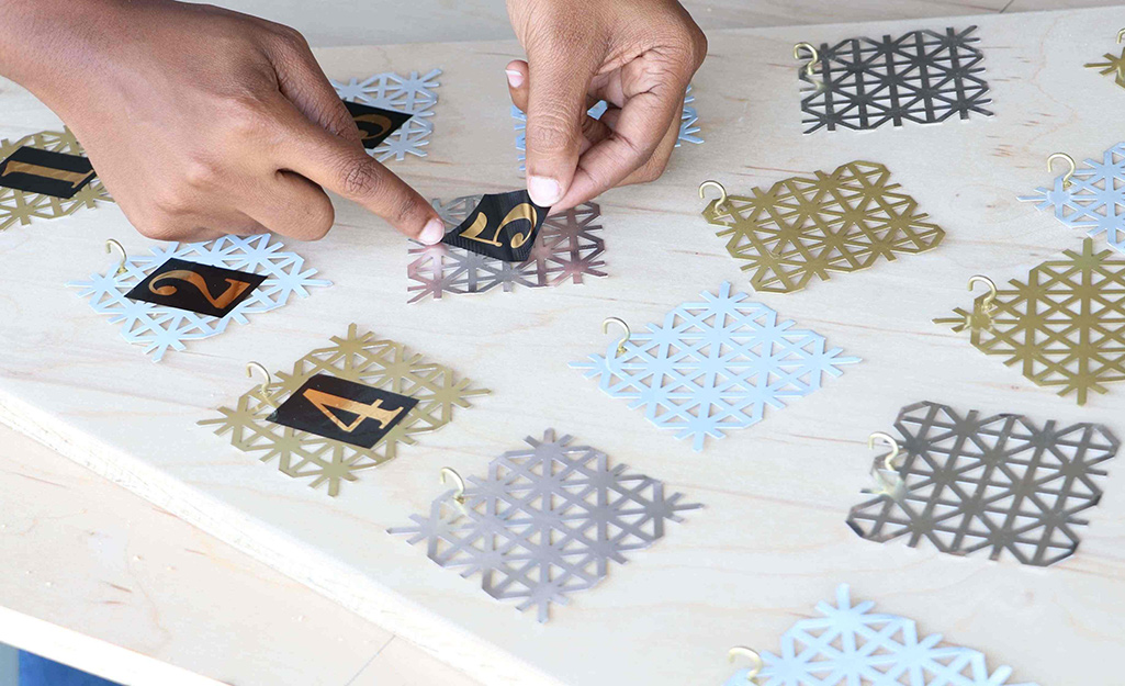 Adhesive numbers are added to metal snowflakes.