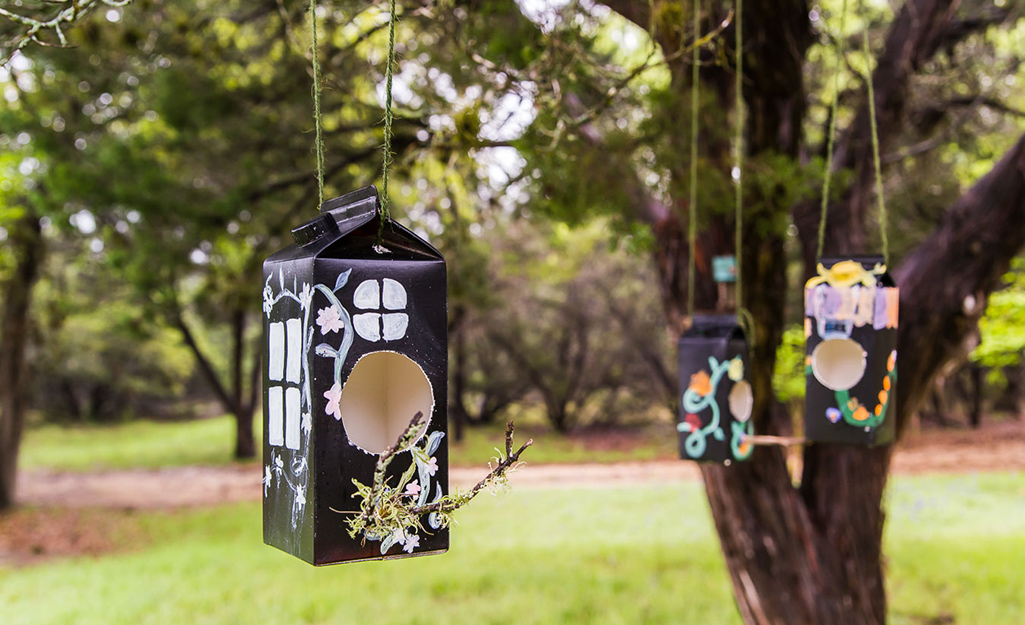 A DIY birdhouse hanging in a yard.