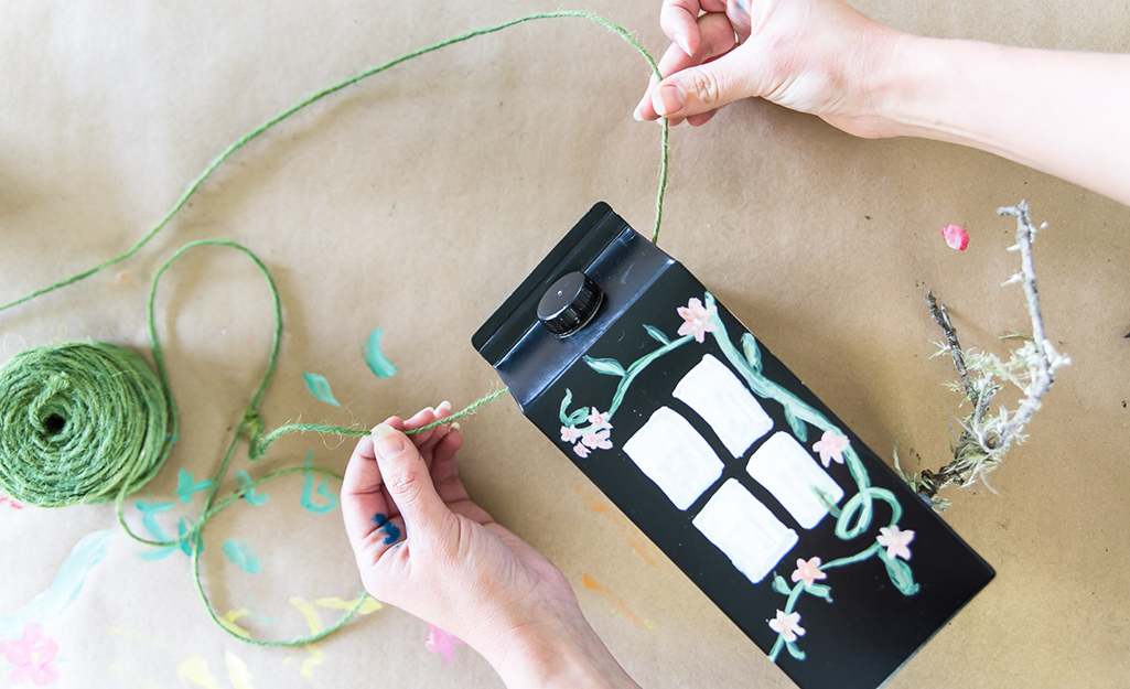 A woman adding string to a carton.