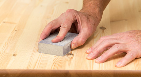 A person sanding a wood surface.