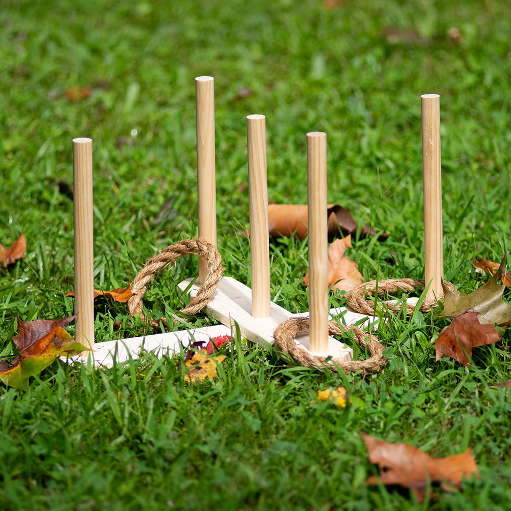 A wooden ring toss game with rope rings on a lawn.