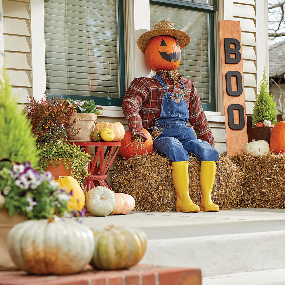 A homemade scarecrow sits on a front porch.
