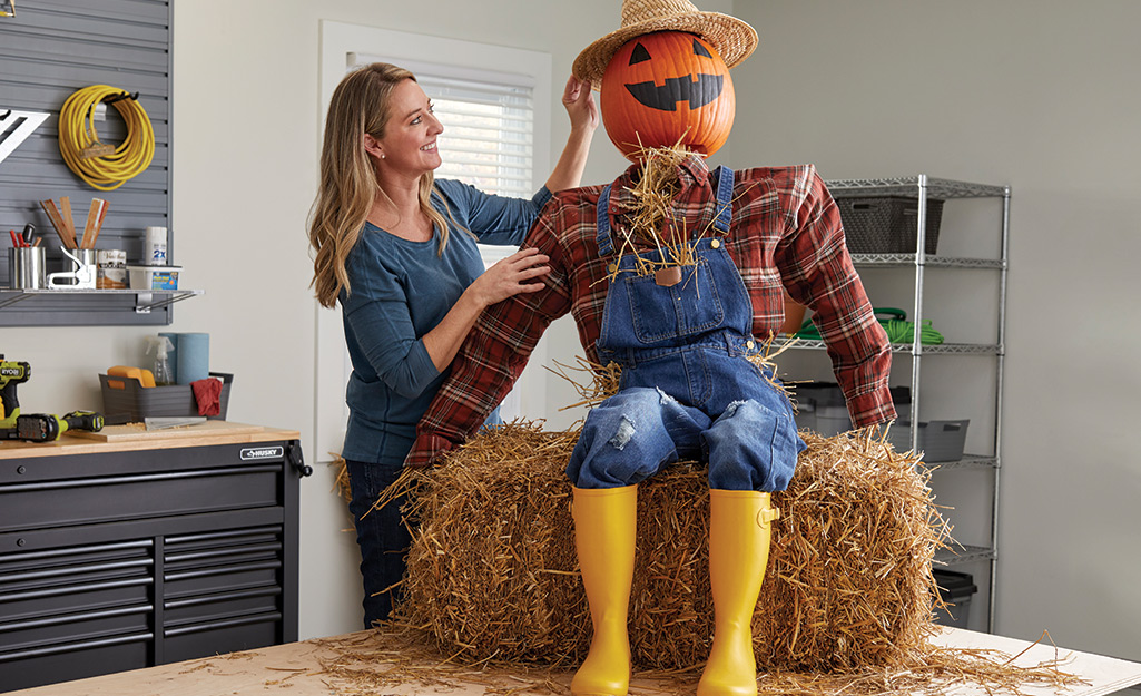 A real pumpkin head with a straw hat completes the DIY scarecrow..