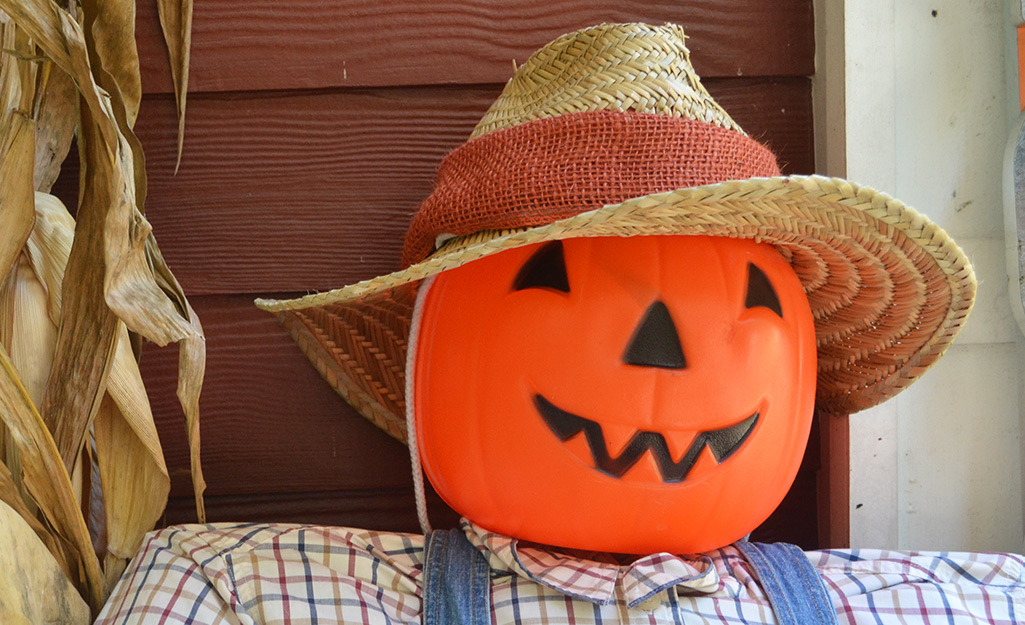 A plastic jack-o-lantern is used as the scarecrow's head.