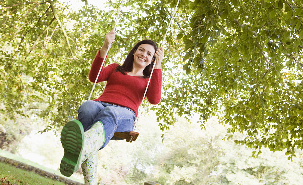 An adult swinging in a tree swing to test that it is secure. An adult swinging in a tree swing to test that it is secure.
