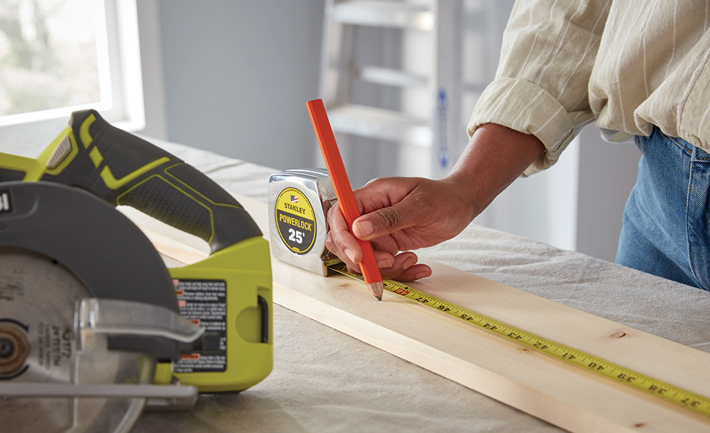 A person measuring and marking wood.