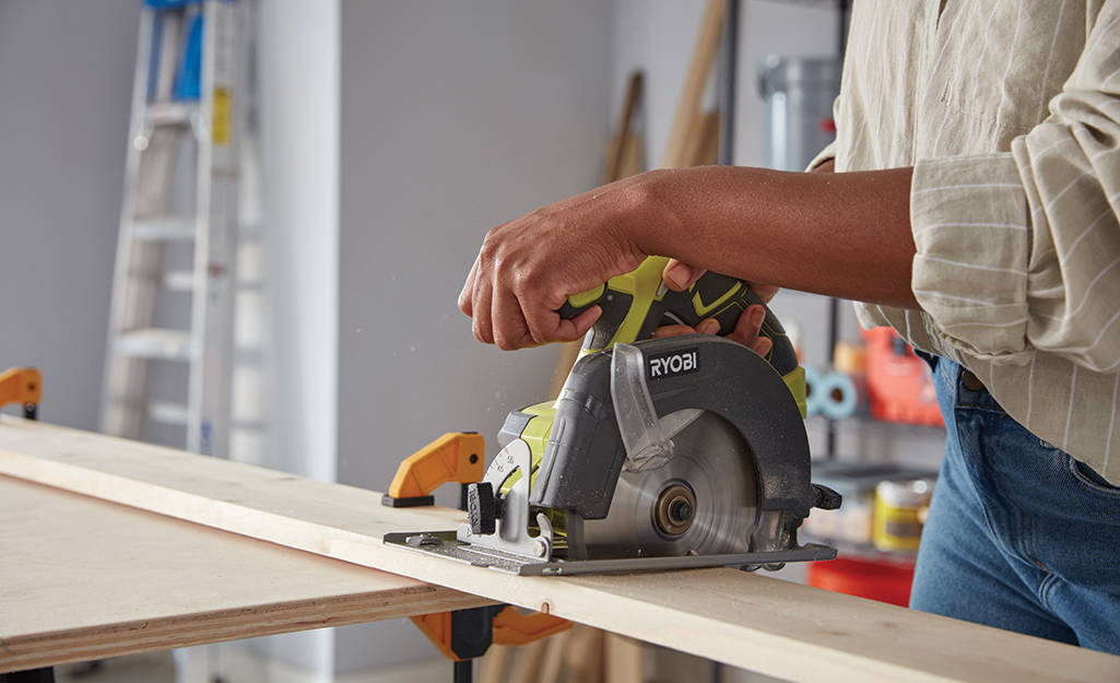 A person using a circular saw to cut wood for a DIY coat hanger.