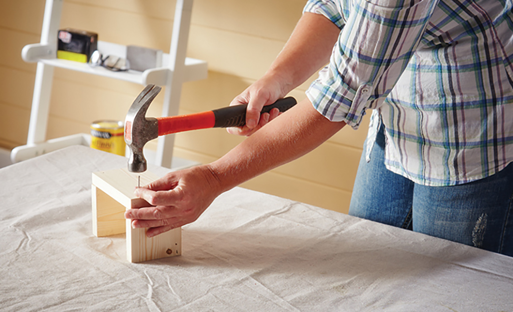 A person hammers wood in place.