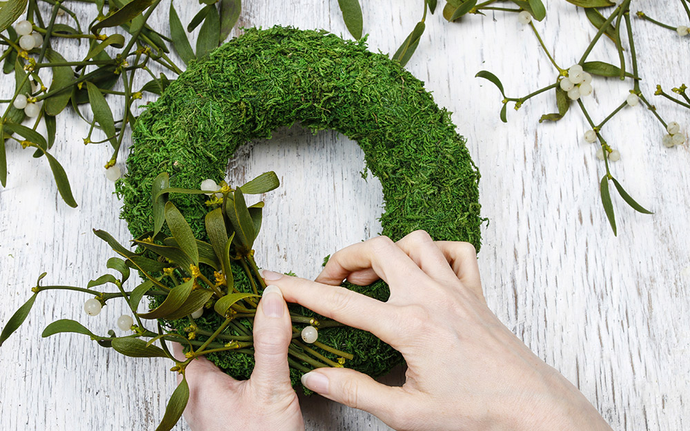 Person making a wreath with greenery.