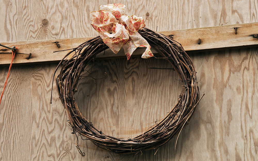 Grapevine wreath with a ribbon hanging on a wall.