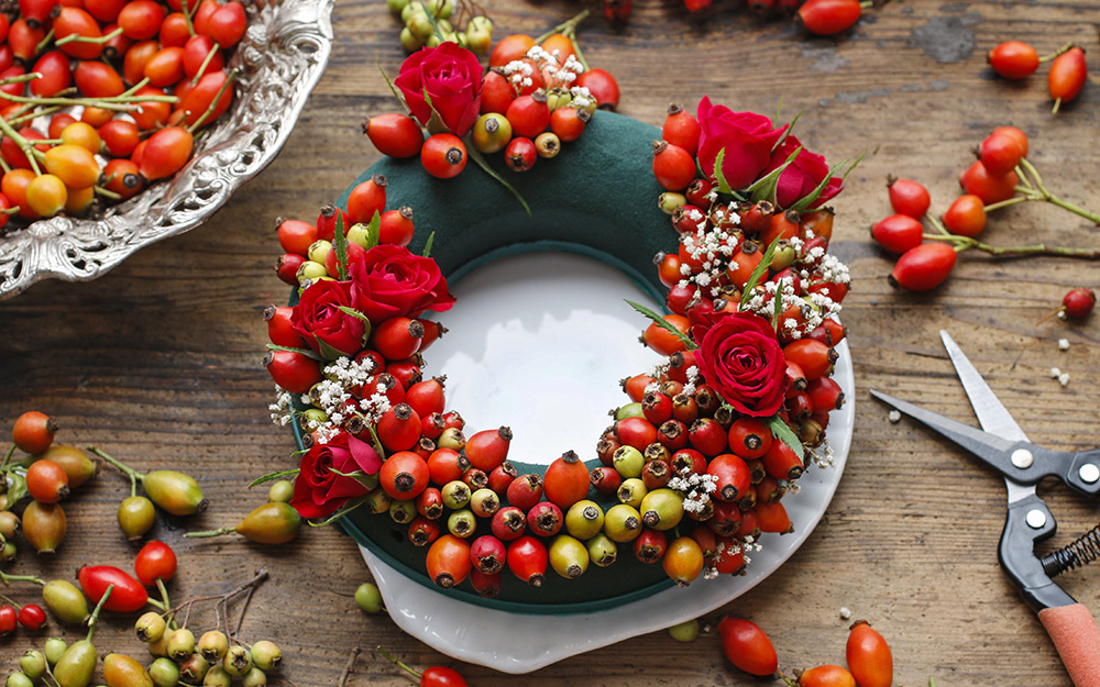 Wreath being made on a foam base with faux flowers and berries.