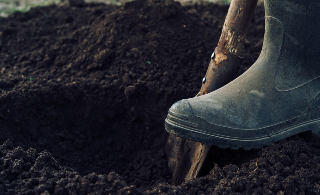 Someone digging a hole in the ground for plants in a Zen garden.