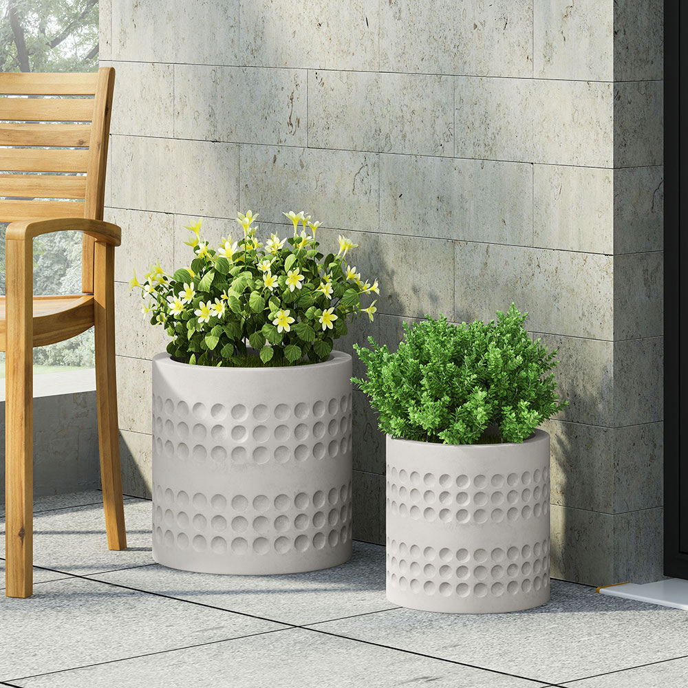Flowers planted in decorative white planters on a porch.