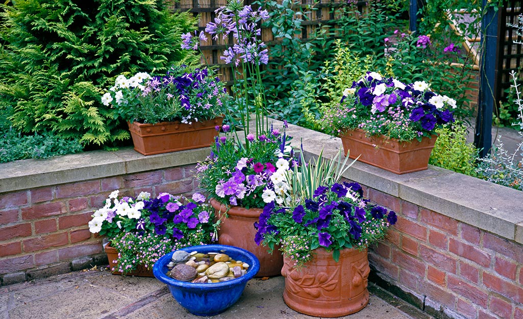 An arrangement of planters filled with flowers on a porch.