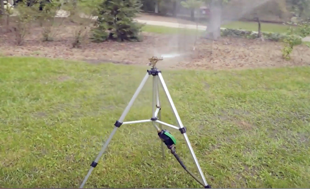 A sprinkler watering a large lawn.