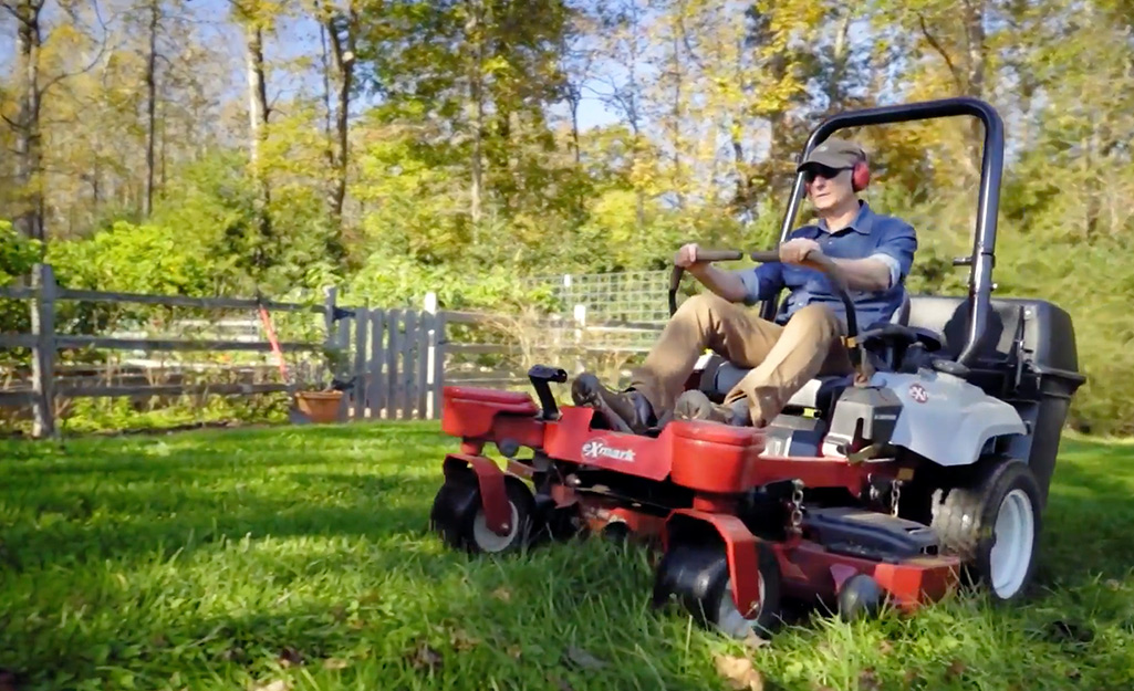 A person using a riding mower to mow a lawn.