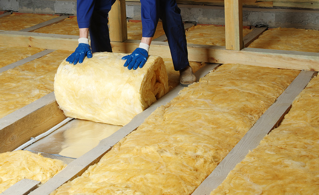A person rolling out insulation.
